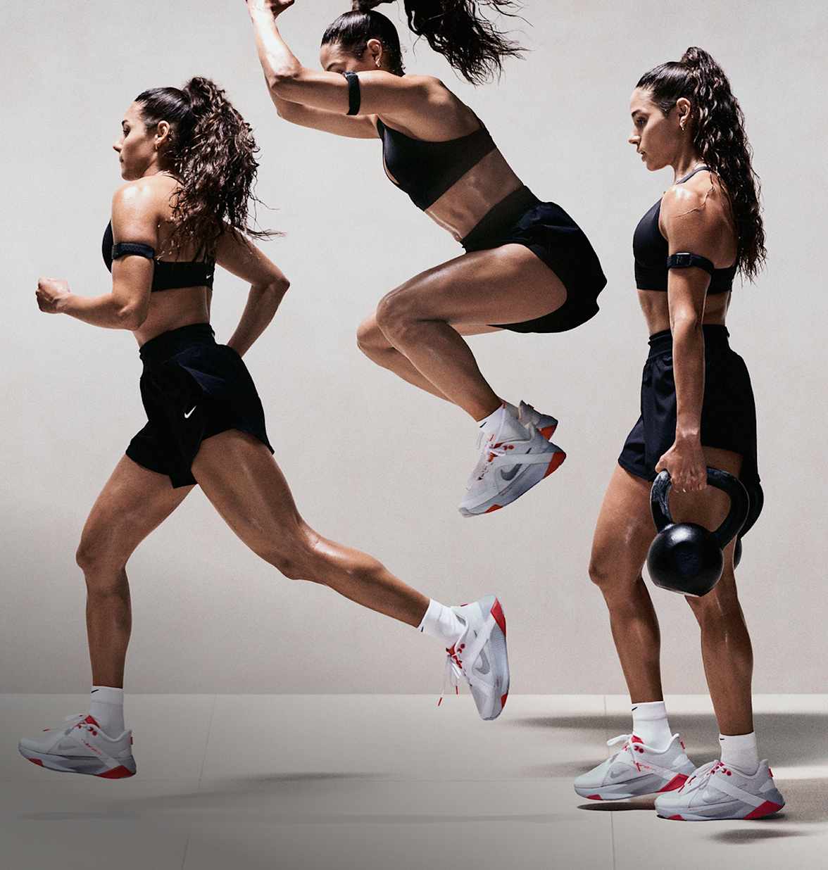 En kvinne utfører forskjellige treningsøvelser i et treningsstudio. Hun har på seg svarte treningsklær og hvite Nike Hybrid RN-treningssko., Hybridklær