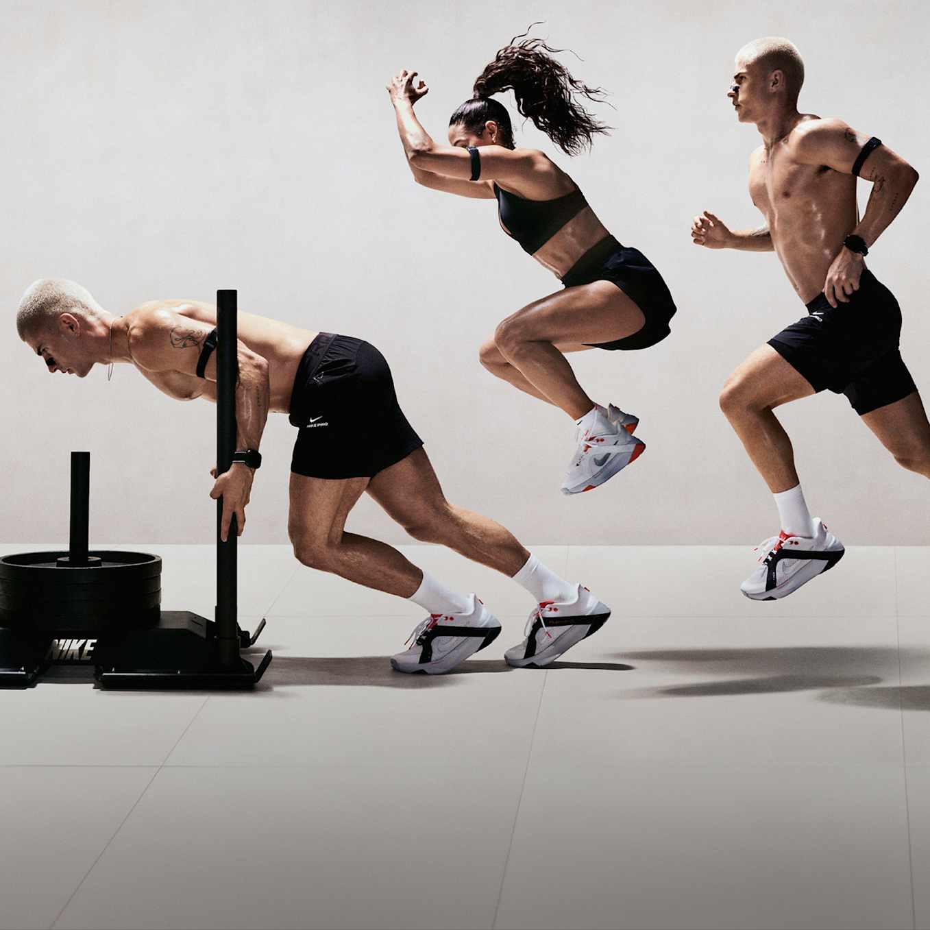 A man and a woman performing various strength and conditioning exercises in a light studio space, wearing black training apparel and Nike Hybrid RN training shoes., Her Antrenmana Hazır Ol