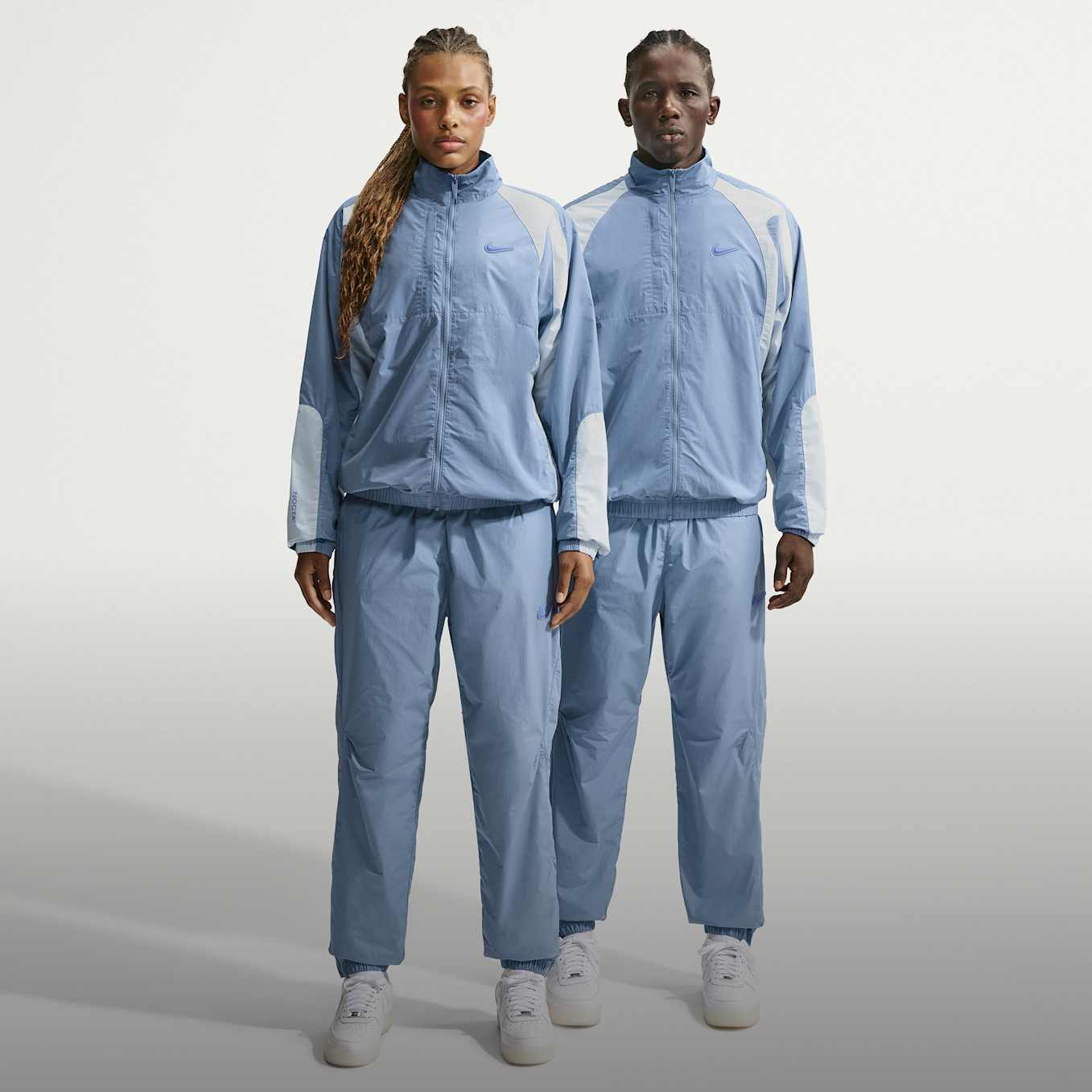 A woman and a man standing in a light grey studio, wearing matching blue and light grey tracksuits and white Nike trainers., Your Everyday, Coordinated