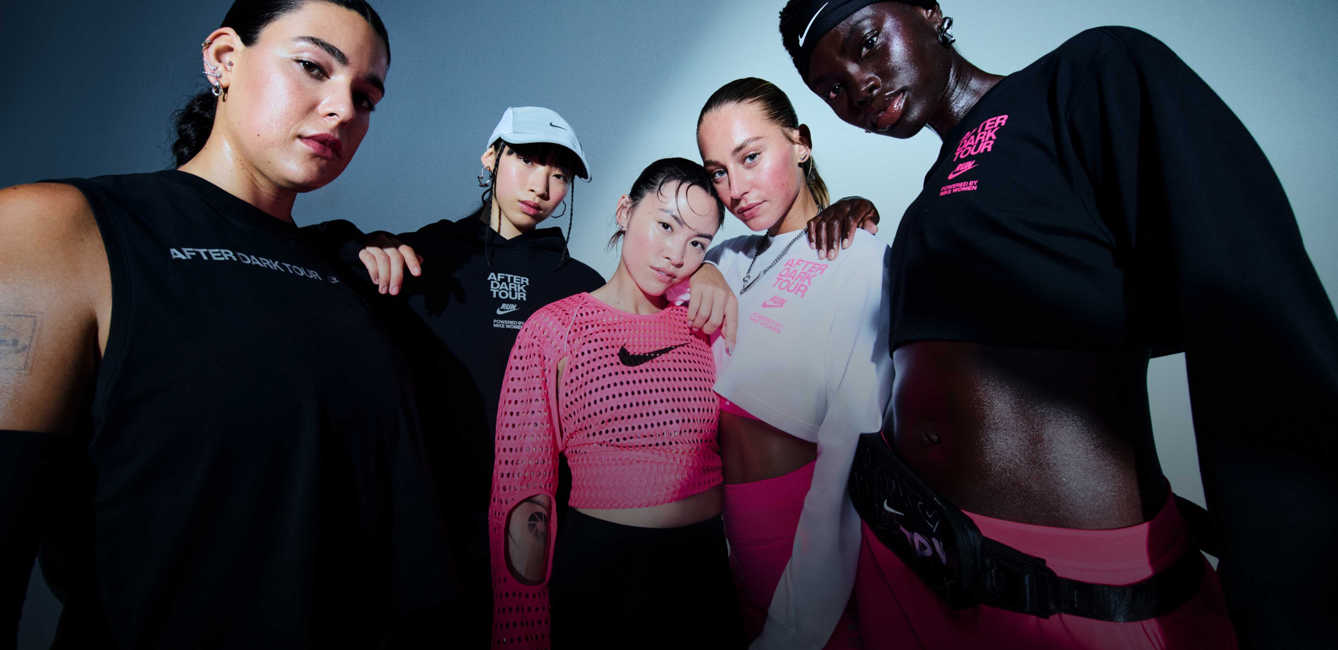 Women standing in a studio space, wearing a grey cap, pink mesh top, and 'After Dark Tour Run' branded apparel., THIS RACE IS PERSONAL