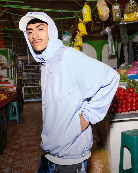 Dépense-toi cet été, Un homme se tient devant un étal. Il porte une veste à capuche Nike bleu clair, une casquette blanche et un short avec des motifs., slide 4 of 5
