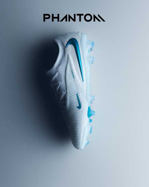 Explore the Bright Lights Pack, A white Nike Phantom football boot displayed on its side on a light grey background, with a blue swoosh, blue cleats, and Nike Gripknit text., slide 3 of 4