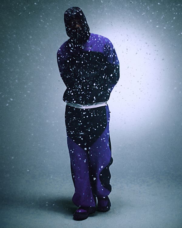 Trending Now, A man standing in falling snow wearing a purple and black hooded Jordan fleece tracksuit and matching shoes., slide 3 of 5