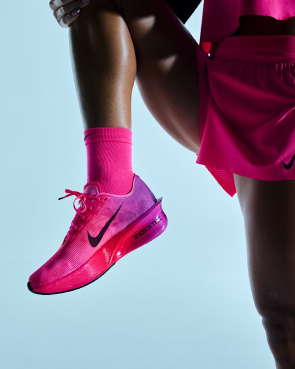 Shop Running, A person stretching in a studio space, wearing a pink Nike running shoe with a pink and purple gradient and pink athletic apparel., slide 2 of 3