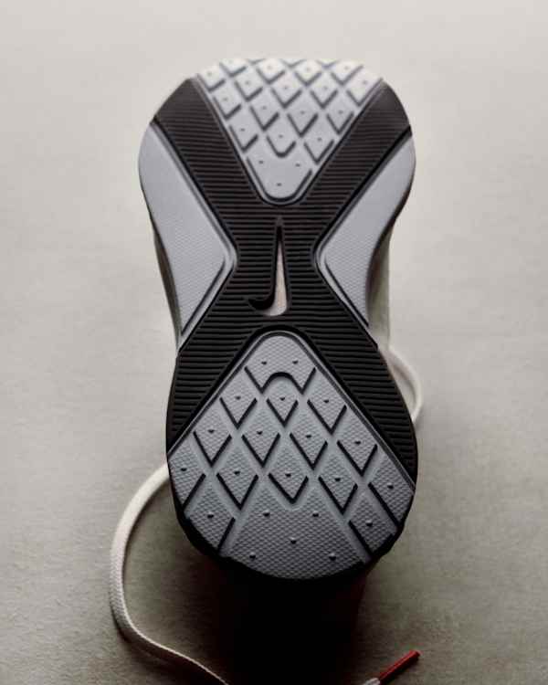 Unes sabatilles per a tots els moviments, La sola exterior de les sabatilles de training Nike Hybrid RN recolzada sobre una superfície gris clar i un cordó blanc., slide 2 of 3
