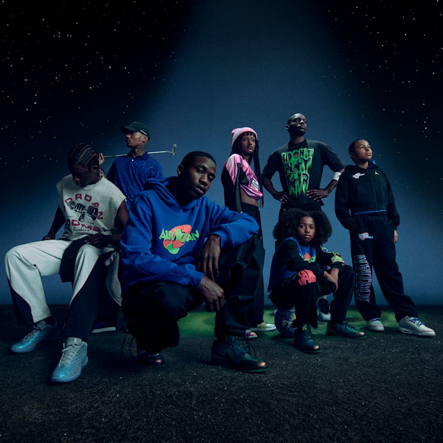 Siedem osób pozuje w blasku reflektora na tle gwiaździstego nocnego nieba, ubranych w kolorową odzież Jordan x Space Jam. Po lewej stronie zdjęcia widoczne są logotypy Jordan Jumpman i „Kosmiczny mecz”., Wielkość jest w zasięgu ręki
