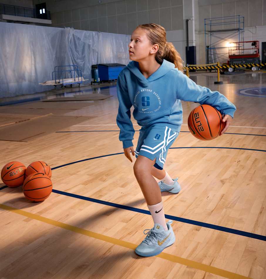 Un niño dribla un balón de básquetbol en una cancha en construcción.