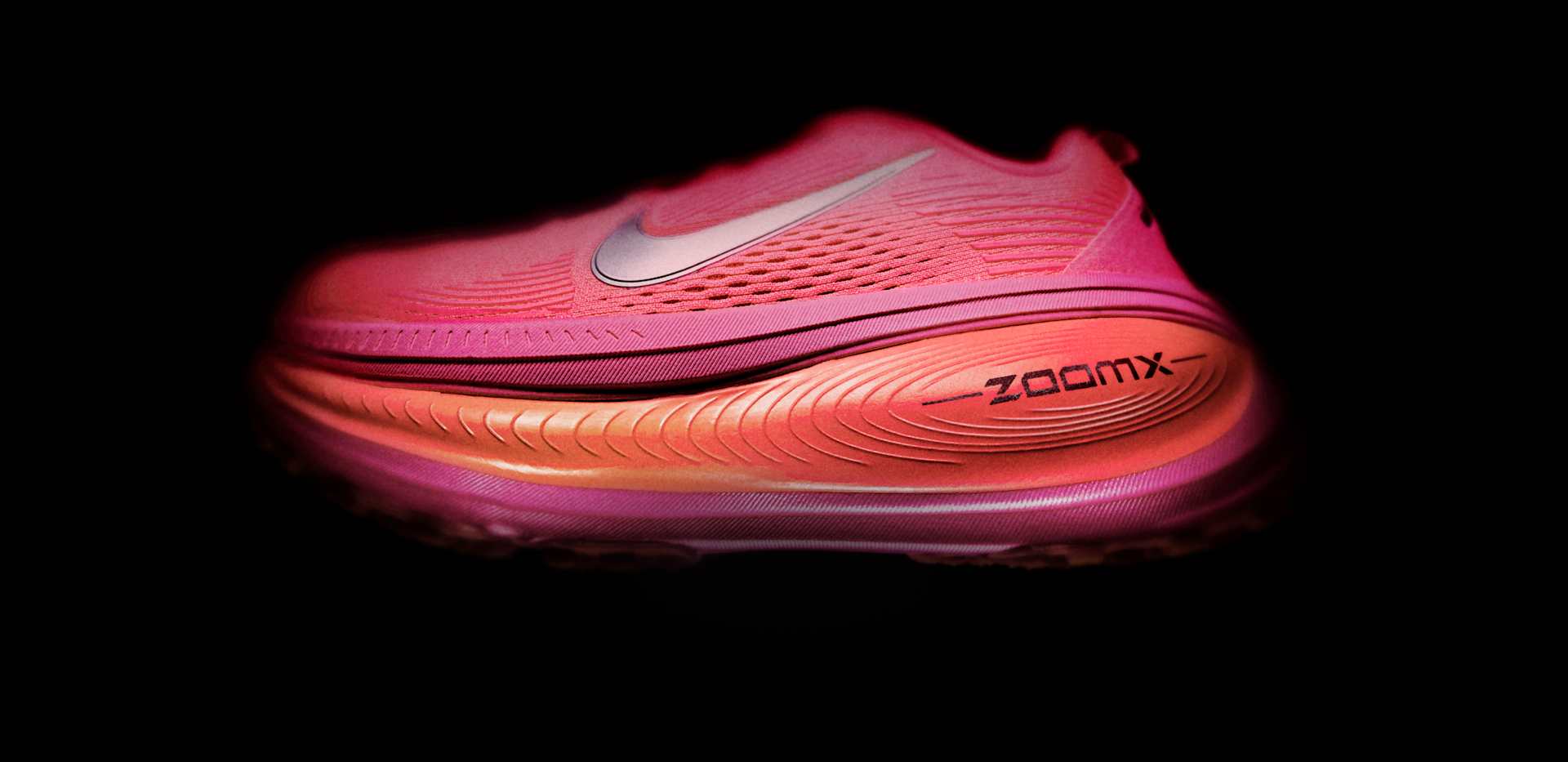 Pink and orange Nike ZoomX Vomero shoe on a black background 