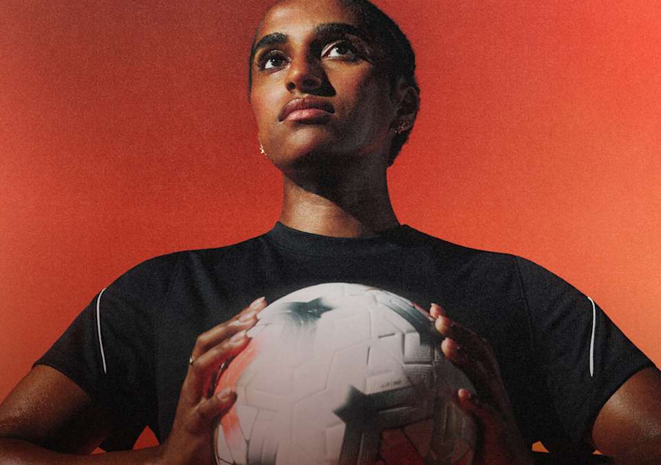 Naomi Girma blickt nach vorne und hält einen Nike Control Fußball nah an sich, vor einem orangefarbenen Hintergrund., Essentials fürs Training