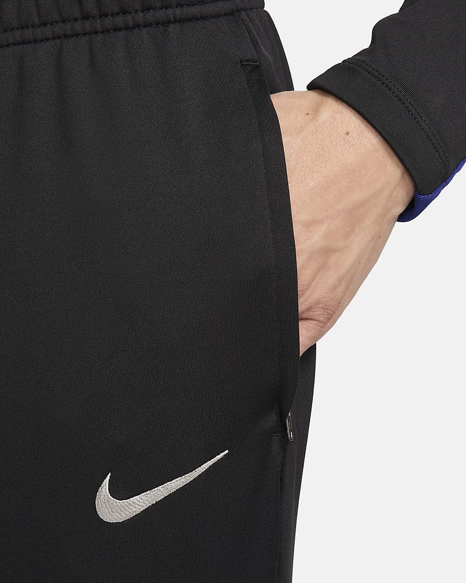 Ανδρικό ποδοσφαιρικό πλεκτό παντελόνι Nike Dri-FIT Μπαρτσελόνα Strike - Μαύρο/Noble Red/Deep Royal Blue/Light Orewood Brown