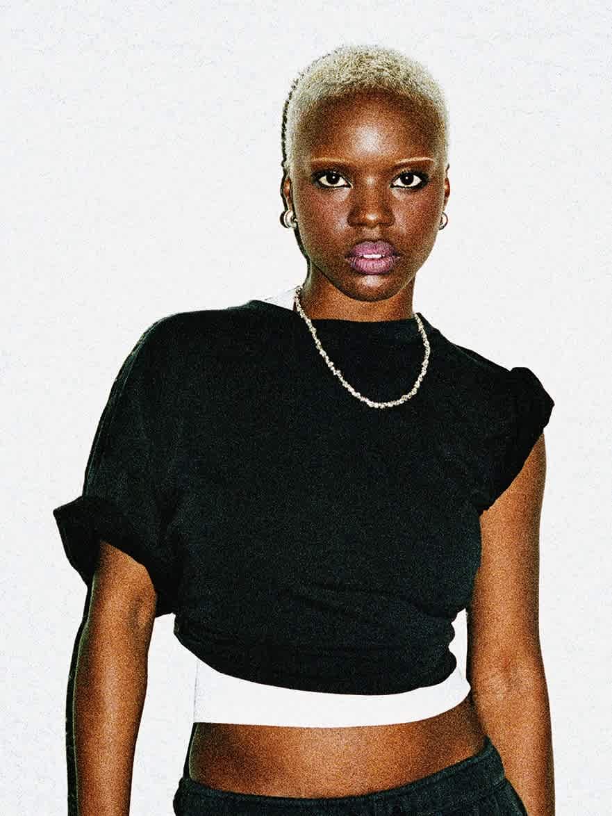 A female model with short blonde hair faces forward wearing a fitted black short-sleeve shirt.