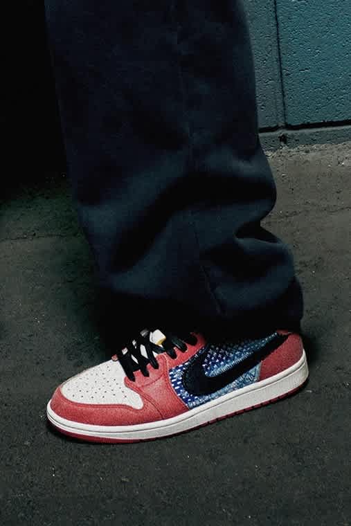 Close-up photo of red, white, blue and black Jordan shoes worn with black sweat pants.