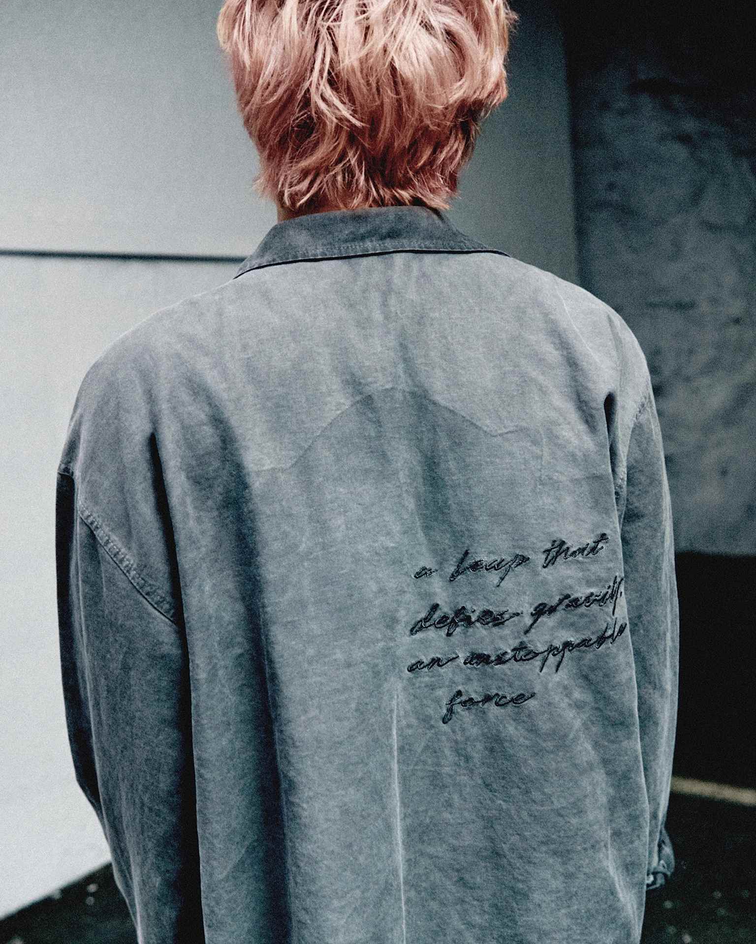 Back view of a male model wearing a loose gray long-sleeve top.