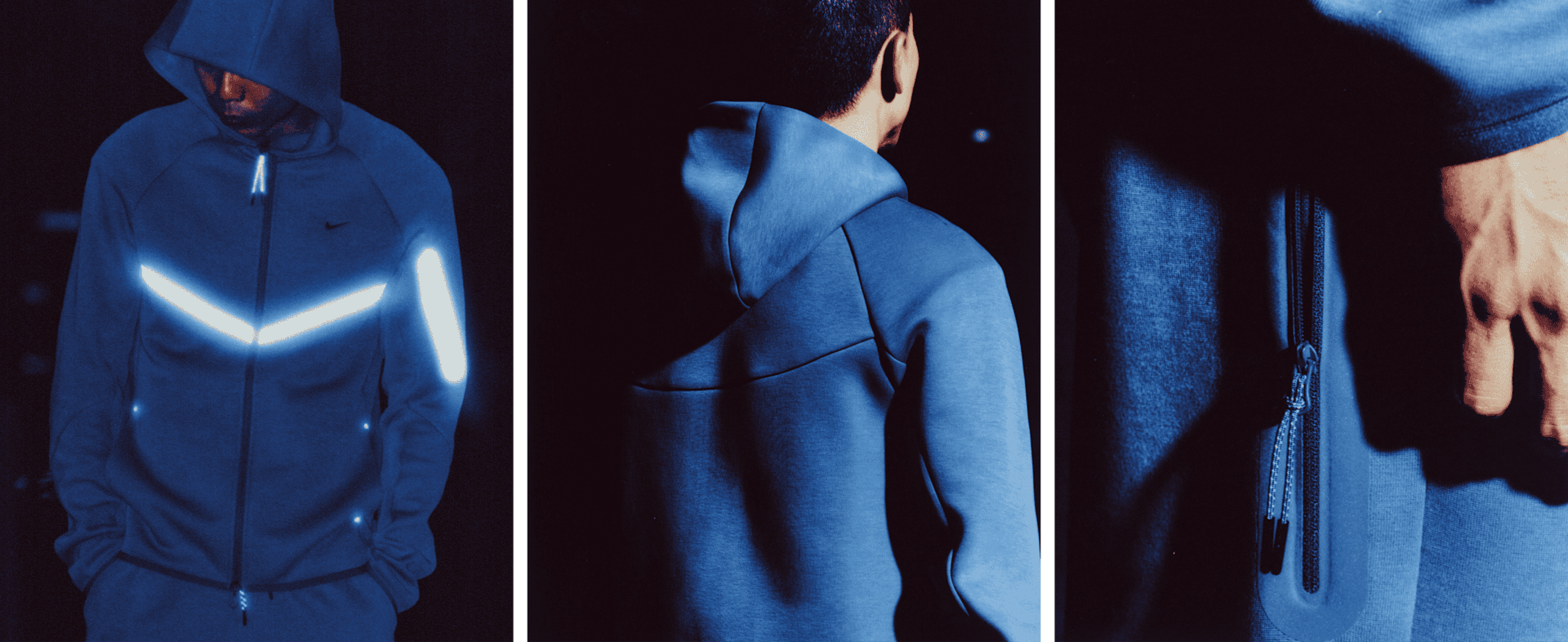 Mężczyzna stoi na zewnątrz w nocy ubrany w niebieską kurtkę Nike Tech Fleece z elementami odbijającymi światło i pasujące do niej spodnie.