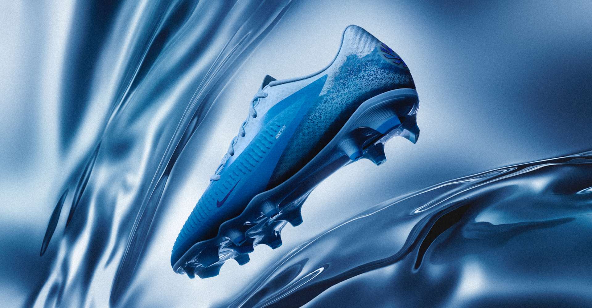 A blue Nike kids' football boot floating against a blue, wavy background.