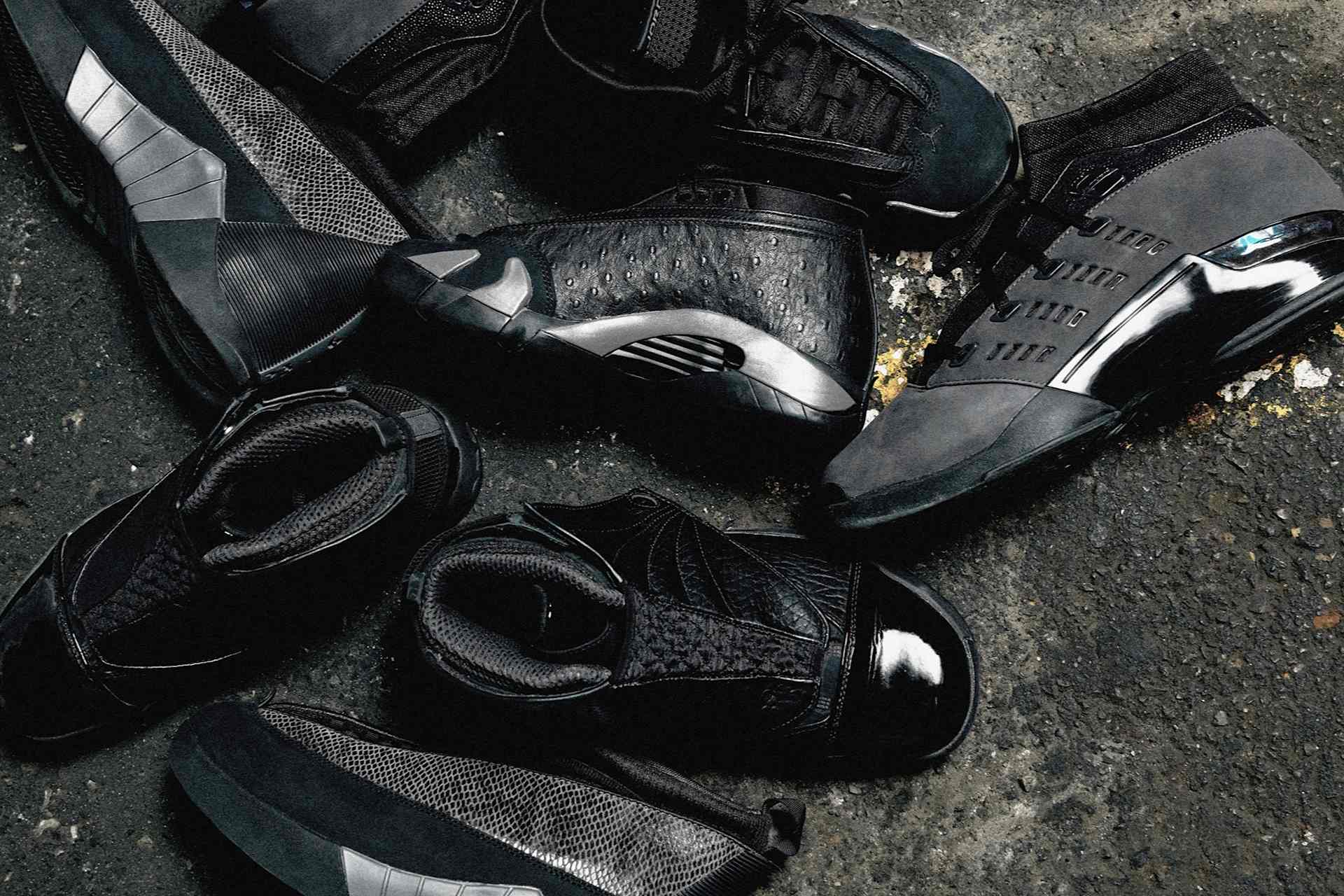 Close-up of a group of black Jordan Brand shoes on a dark, textured surface.